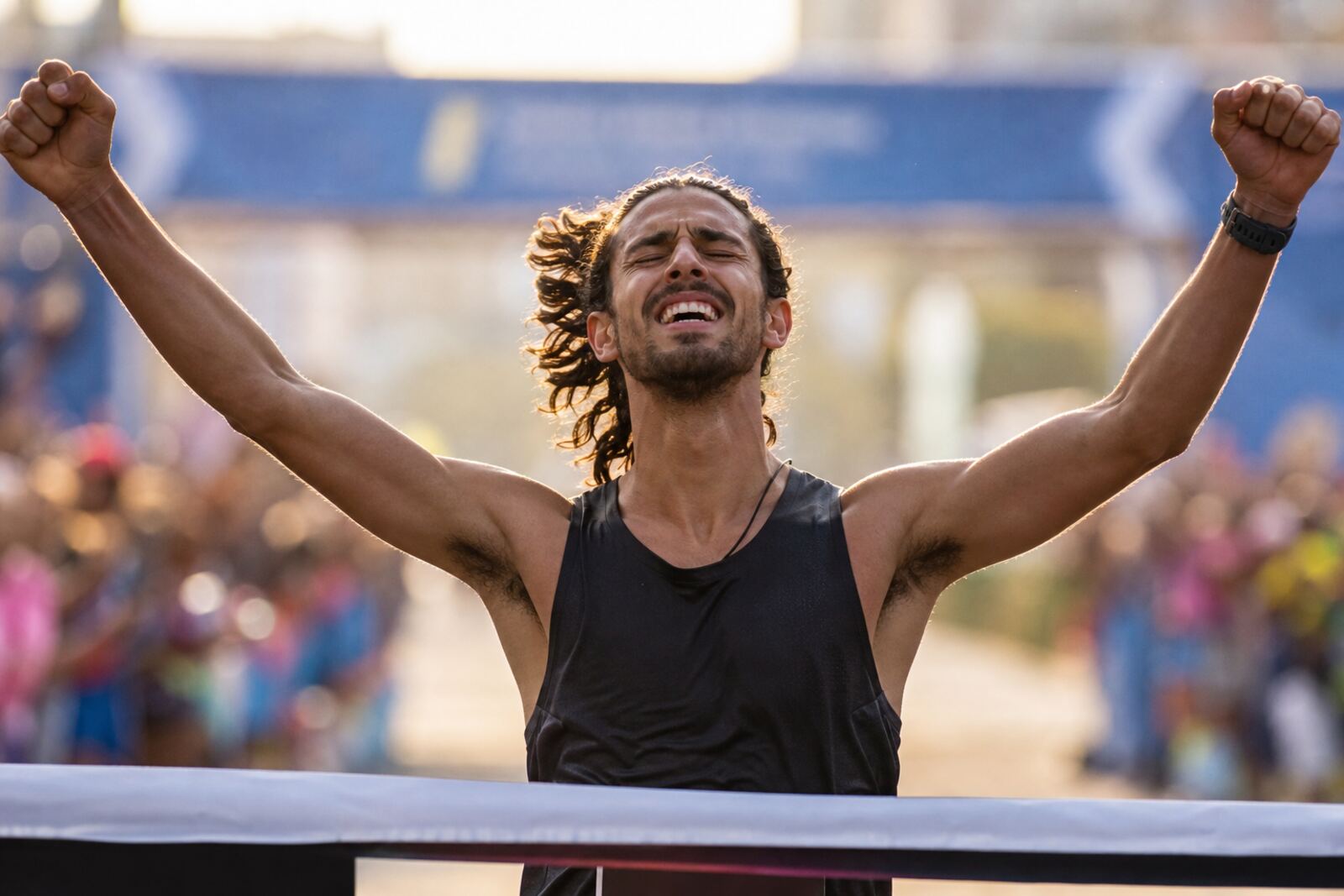 Läufer überquert die Marathon-Ziellinie mit erhobenen Armen.